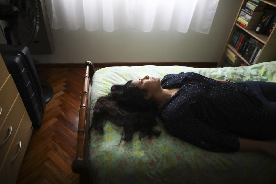 Camila Fernandez poses for a photo on her bed during a government-ordered lockdown to curb the spread of the new coronavirus in Buenos Aires, Argentina, Monday, June 29, 2020. The 26-year-old who works at the prosecutor's office lives alone in her apartment in the company of books, of which she has read more than 20 during quarantine, while studying to become a public translator and English teacher. "Quarantine is an ideal state," said Fernandez. ( AP Photo/Natacha Pisarenko)