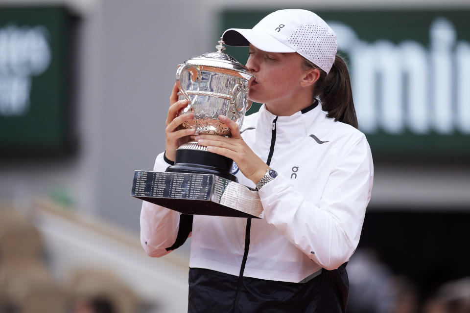 Iga Swiatek poses with the Roland Garros trophy.