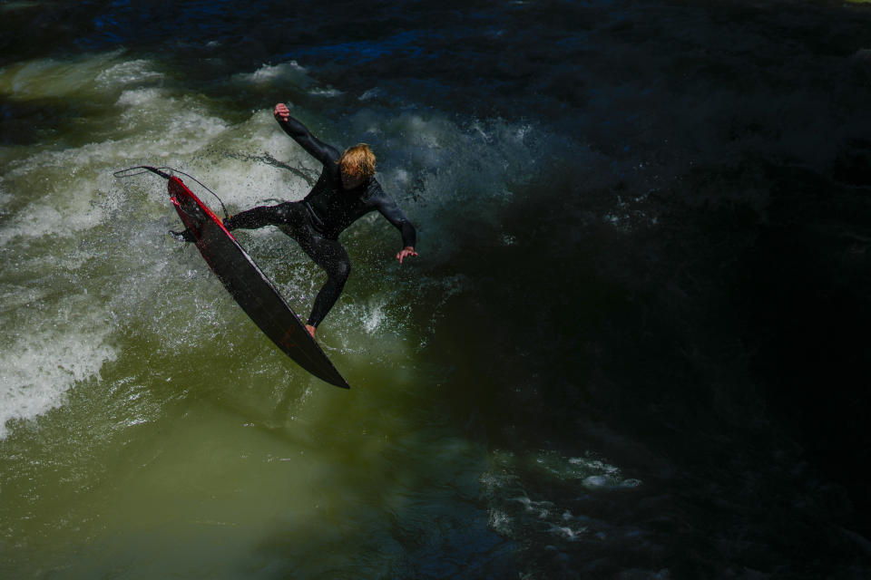 A surfer rides on an artificial wave in the river 'Eisbach' at the 'Englischer Garten' (English Garden) downtown Munich, Germany, Tuesday, June 18, 2024, during the the Euro 2024 soccer tournament that takes place in Germany from June 14 until July 14. (AP Photo/Ariel Schalit)