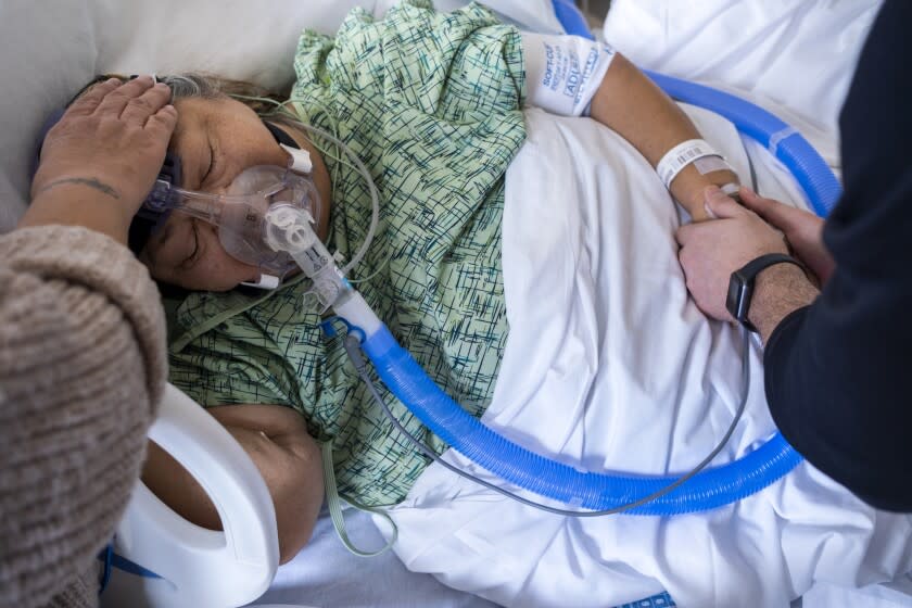 MISSION HILLS, CA - JANUARY 12: Chaplain Kevin Deegan, right, prays with Marylou Samora, 72, of San Fernando at Providence Holy Cross Medical Center on Wednesday, Jan. 12, 2022 in Mission Hills, CA. She is a covid19 patient has been in the hospital for 51 days. (Francine Orr / Los Angeles Times)