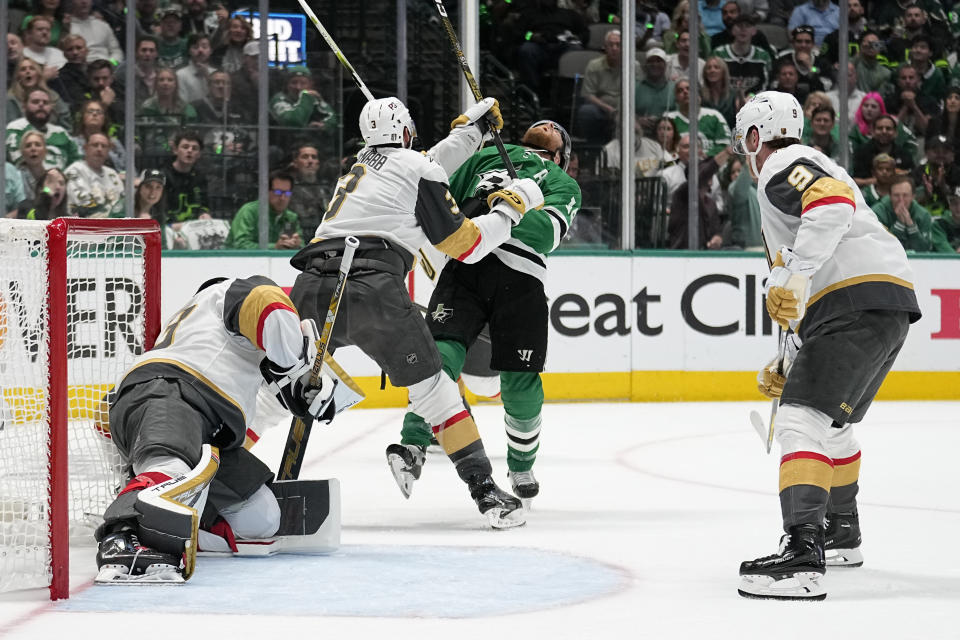 Dallas Stars center Joe Pavelski, center, takes a stick to the face from Vegas Golden Knights' Brayden McNabb (3) during the first period of Game 4 of the NHL hockey Stanley Cup Western Conference finals, Thursday, May 25, 2023, in Dallas. McNabb was called for high-sticking. In the foreground are Golden Knights' Adin Hill, left, and Jack Eichel. (AP Photo/Tony Gutierrez)