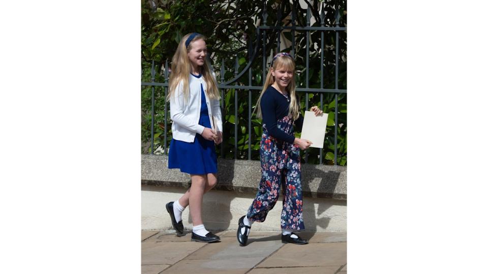 Savannah Phillips in a white coat and blue dress with Isla Phillips in floral trousers and blue cardigan