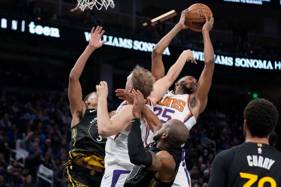 Phoenix Suns guard Mikal Bridges (25) rebounds the ball next to Golden State Warriors guard Jordan Poole, left, during the second half of an NBA basketball game in San Francisco, Tuesday, Jan. 10, 2023. (AP Photo/Godofredo A. Vásquez)