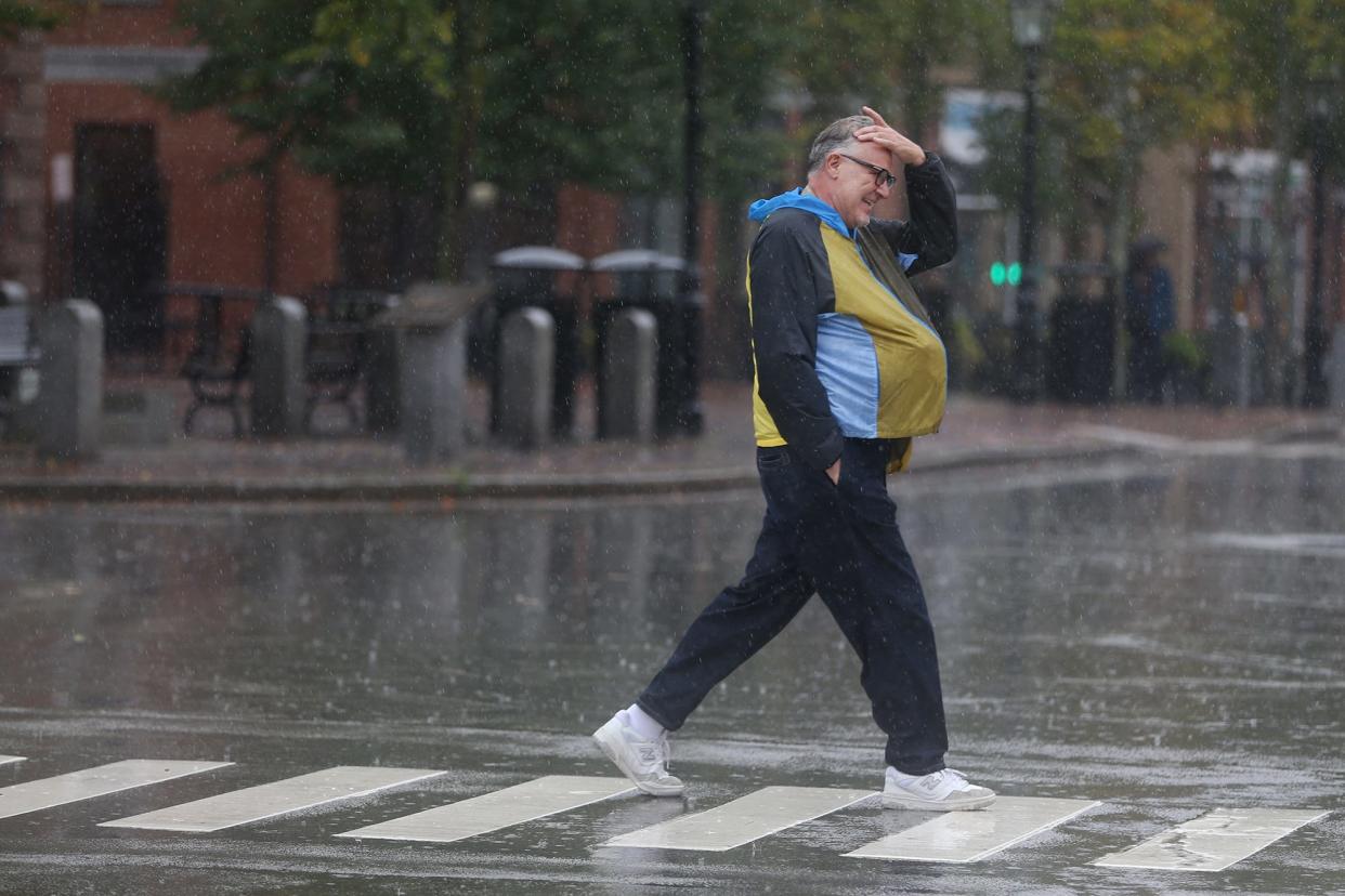 A pedestrian crosses the street in Portsmouth during the rain storm Thursday, September 22, 2022.