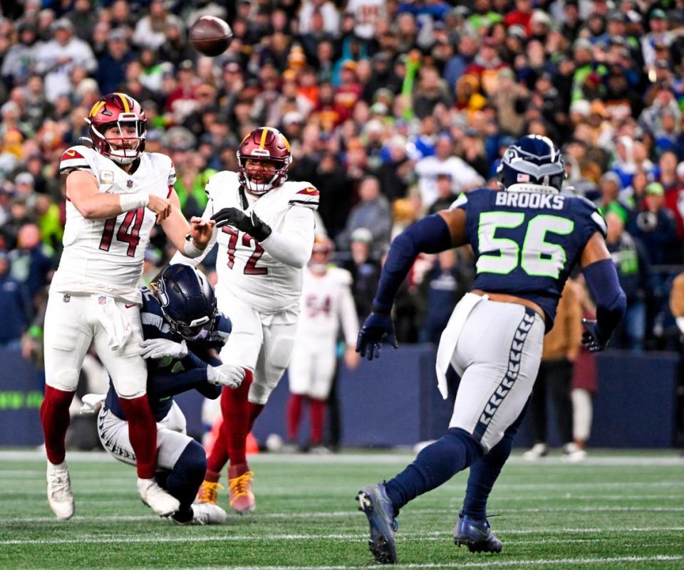 Washington Commanders quarterback Sam Howell (14) throws while being hit by Seattle Seahawks linebacker Darrell Taylor (52) during the fourth quarter of the game at Lumen Field, on Sunday, Nov. 12, 2023, in Seattle, Wash.