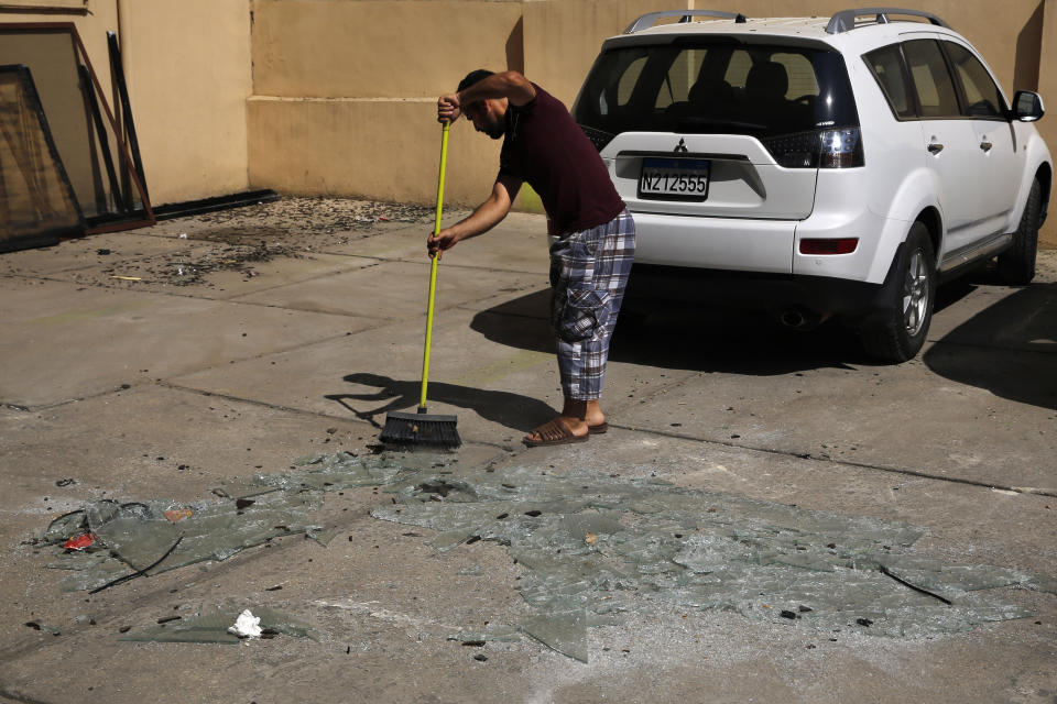 A man sweeps broken glass near the 11th-floor building that houses the media office in a stronghold of the Lebanese Hezbollah group, in a southern suburb of Beirut, Lebanon, Sunday, Aug. 25, 2019. Two Israeli drones crashed into the Hezbollah stronghold in the Lebanese capital overnight without the militants firing on them, a spokesman for the group said Sunday, saying the first fell on the roof of a building housing Hezbollah's media office while the second landed in a plot behind it. (AP Photo/Bilal Hussein)