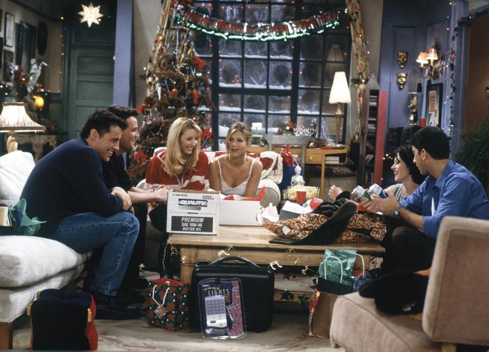 a group of people sitting around a table with a christmas tree