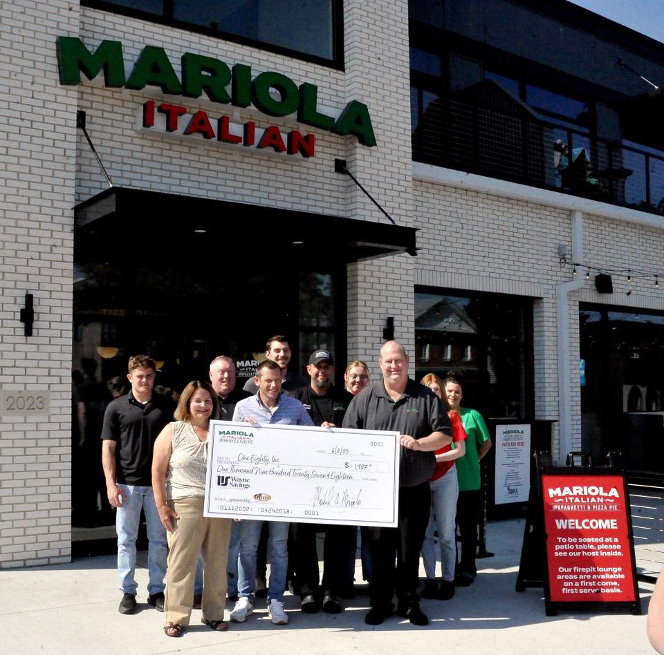Restauranteur Mike Mariola and employees give OneEighty Executive Director Bobbie Douglas a check for roughly $1,927. It was fundraised during Mariola Italian's first week in business.