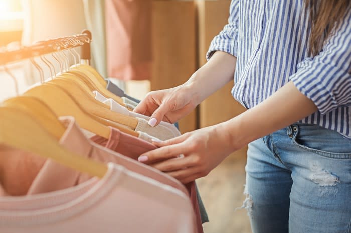 Woman thumbing through shirts hanging on a rack