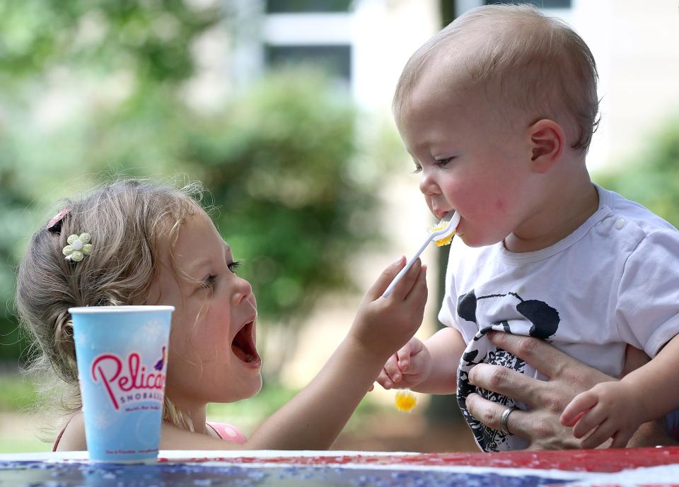 Three-year-old Willow Dry gives her younger sister, Aurora Dry, a bite of her snow cone during the North Carolina American Legion 7th Inning Stretch Festival held Saturday, Aug. 6, 2022, in Uptown Shelby.