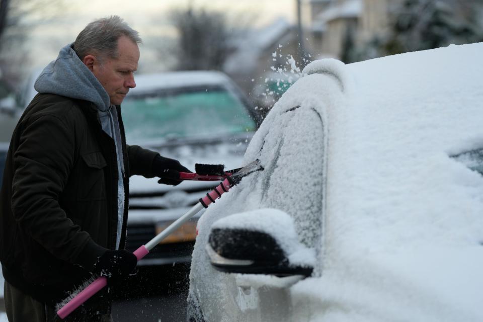 Lenny Bloomfield, of East Rutherford, uses two ice scrapers to clear his girlfriend's car of snow in East Rutherford, N.J. on Monday Dec. 12, 2022.