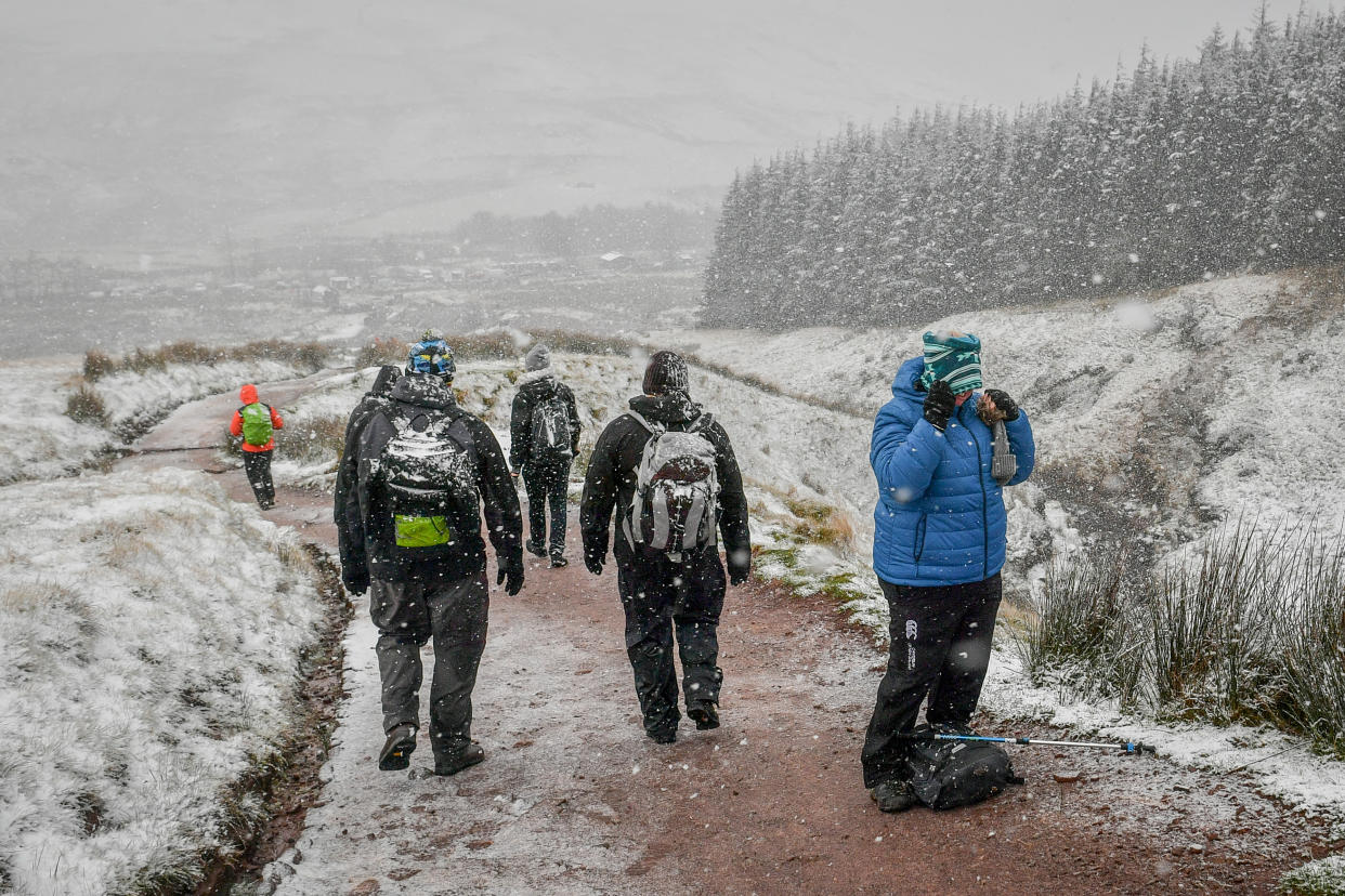 A woman pauses to pull on a snood as she hikes up Pen y Fan as snow falls on the Brecon Beacons National Park, Wales, as much of the UK experiences wintry weather on the first weekend of December, with warnings in place for ice and snow.