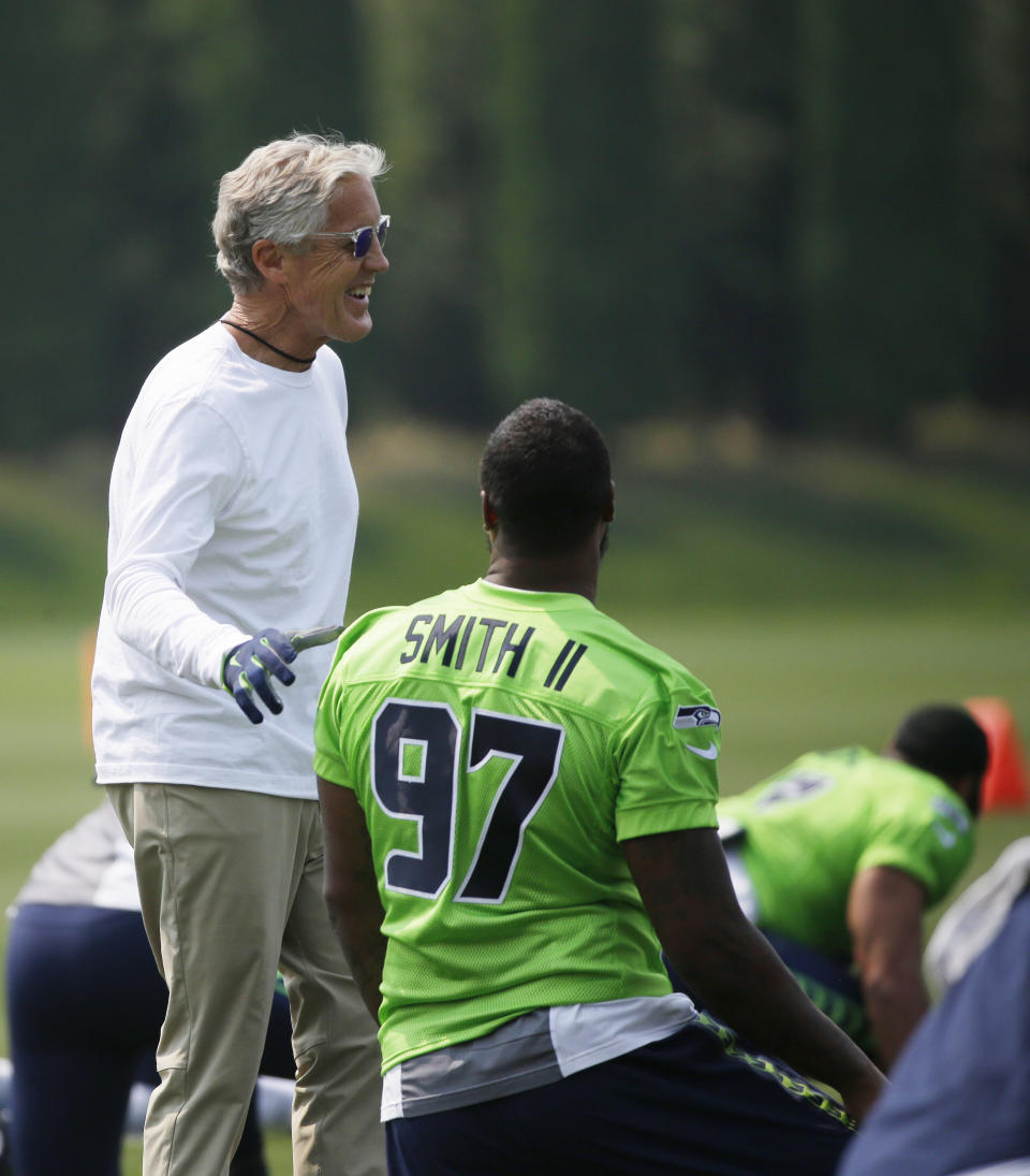 FILE - Seattle Seahawks head coach Pete Carroll, left, talks with defensive end Marcus Smith (97) during stretching before an NFL football training camp, Monday, Aug. 7, 2017, in Renton, Wash. Marcus Smith III nearly tried to commit suicide because of pressure from football. He went to practice and told coach Pete Carroll and defensive line coach Cliff Hurtt what happened. “He supported me in every way possible. He actually helped me get that therapist, let me know that everything was going to be fine,” Smith said of Carroll. (AP Photo/Ted S. Warren, File)