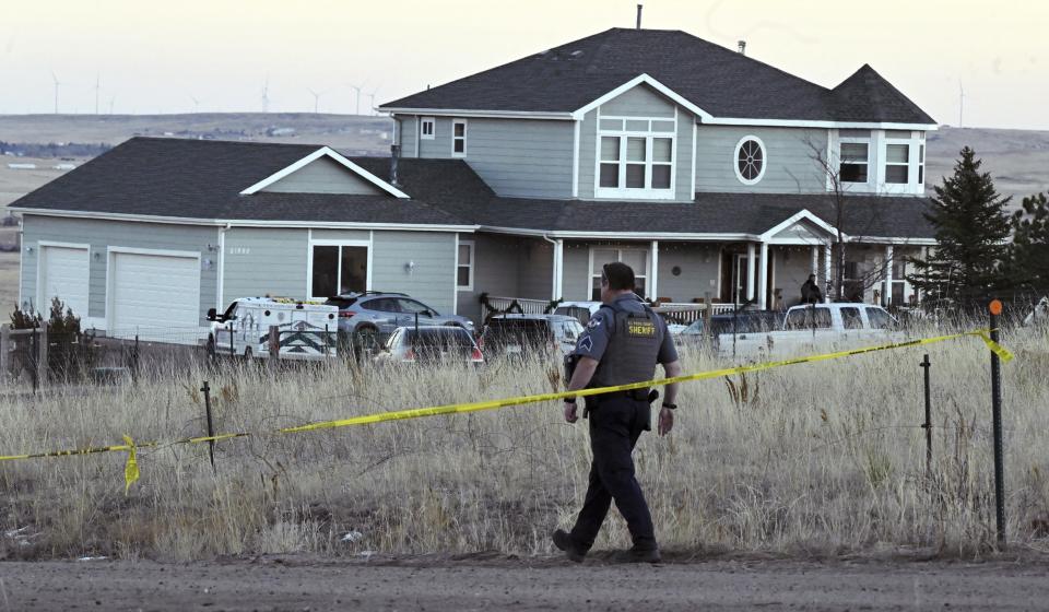 FILE - A sheriff's deputy from the El Paso County Sheriff's Department walks down the road after reattaching crime scene tape across the road that leads to a house, Dec. 7, 2023, in Peyton, Colo. On Tuesday, Dec. 12, Colorado authorities released the identities of four people, including three family members, who were found dead inside the home in rural Colorado following a reported shooting the week before. (Jerilee Bennett/The Gazette via AP, File)