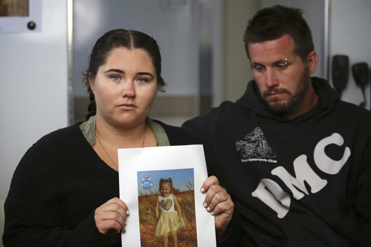 Ellie Smith, left, and her partner Jake Gliddon, display a photo of their missing daughter, Cleo, near Carnarvon in Western Australia state, Australia, Oct. 19, 2021. Cleo was rescued "alive and well" on Wednesday, Nov. 3, 2021, more than three weeks after she was suspected to have been snatched from a tent during a family camping trip on Australia's remote west coast, police said. (James Carmody/AAP Image/Pool via AP)