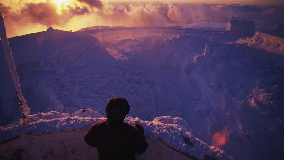 A hiker looks out over Mount Washington from an observation deck in the White Mountains