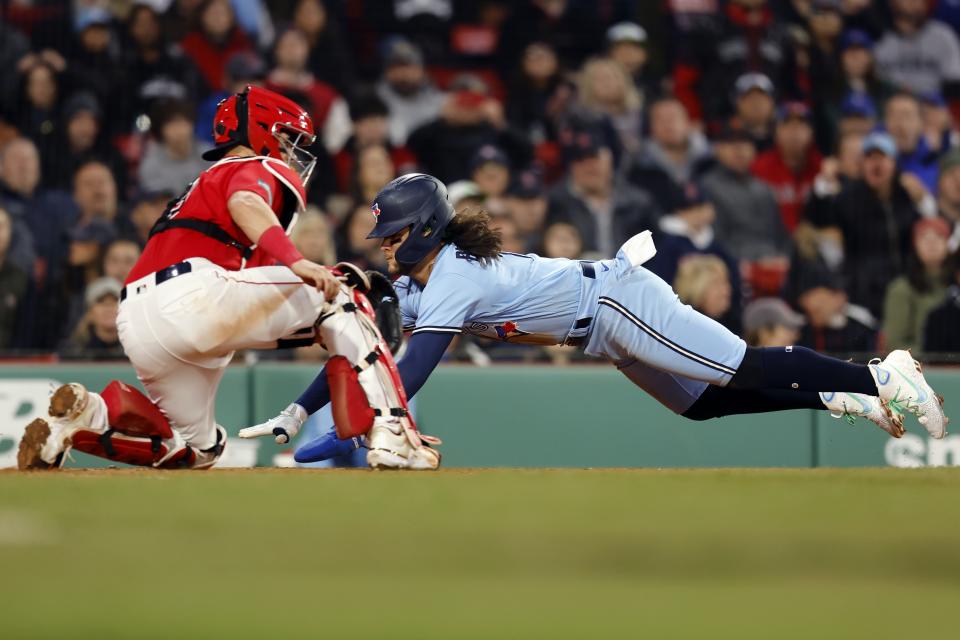 Toronto Blue Jays' Bo Bichette, right, scores against Boston Red Sox's Reese McGuire, left, on a sacrifice fly by Daulton Varsho during the fifth inning of a baseball game, Thursday, May 4, 2023, in Boston. (AP Photo/Michael Dwyer)
