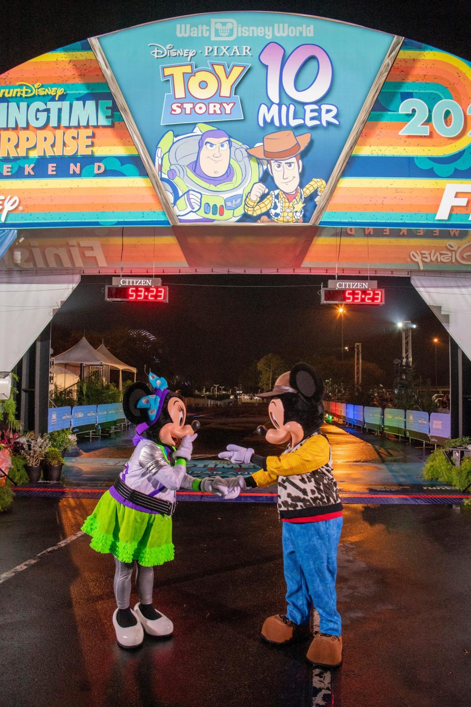 Mickey Mouse and Minnie Mouse pose near the finish line as they await the first finishers of the Disney Pixar Toy Story 10-Miler during runDisney Springtime Surprise Weekend on April 16, 2023, at Walt Disney World Resort in Lake Buena Vista, Fla. (Kent Phillips, photographer)