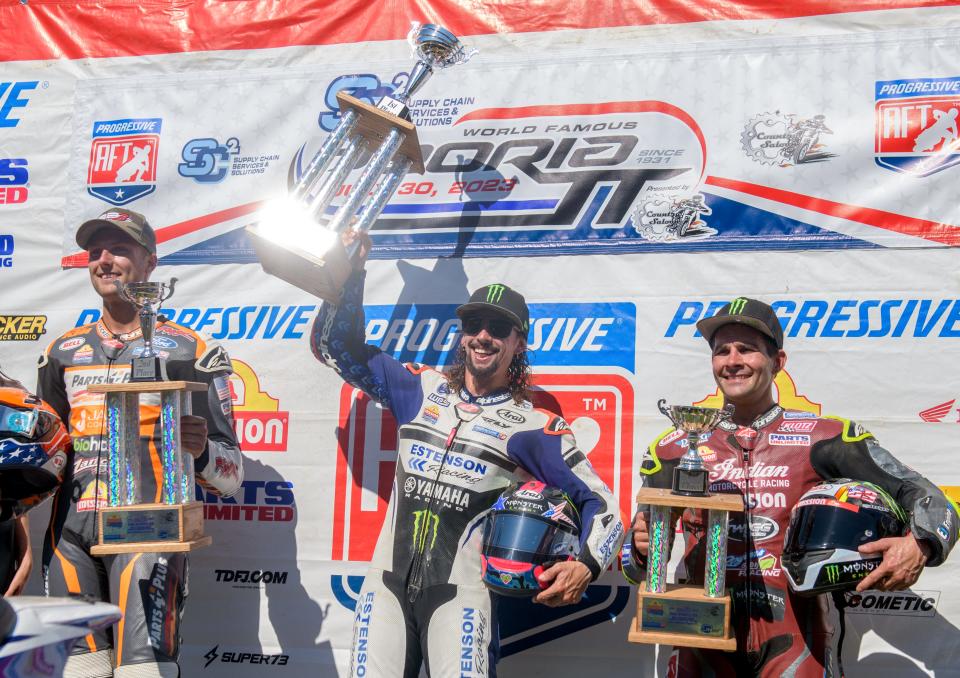 The sun shines off the first-place trophy as rider JD Beach, middle, celebrates his victory in the Progressive American Flat Track SC2 Peoria TT Mission SuperTwins Main Event motorcycle race Sunday, July 30, 2023 at the Peoria Motorcycle Club. Beach led the entire race to victory. Briar Bauman, left, was second and Jared Mees was third.