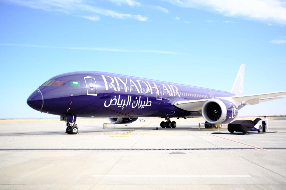 A Riyadh Air Boeing 787 Dreamliner in purple livery on the tarmac at the Dubai Air Show 2023.