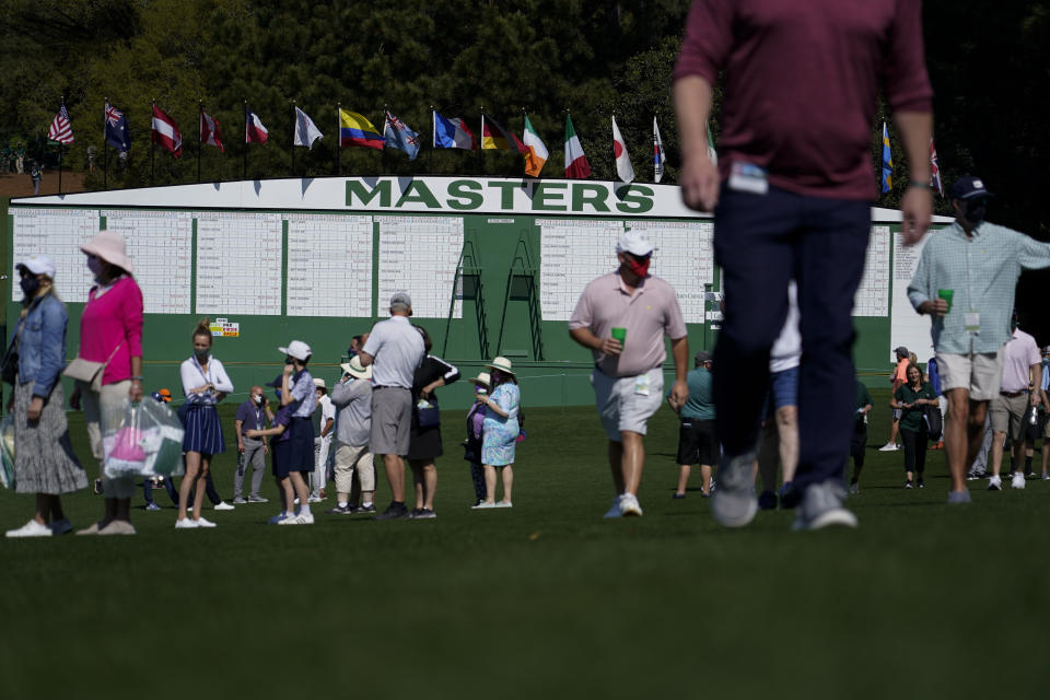 Patrons walk by the main scoreboard during a practice day for the Masters golf tournament on Tuesday, April 6, 2021, in Augusta, Ga. (AP Photo/Gregory Bull)