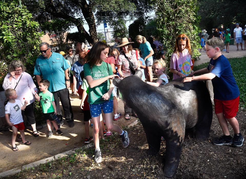 Families crowd around the latest addition to the Adamson-Spaulding Storybook Garden Thursday, artist Sophie Blackall's Winnie, a bronze bear by artist Steve Neves based upon Blackall's illustrations for the book "Finding Winnie."