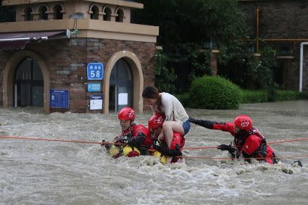 Firefighters rescue a stranded woman on a flooded street, following heavy rainfall in Chengdu, Sichuan province, China July 11, 2018. Picture taken July 11, 2018. Wang Hongqiang/Chengdu Economic Daily via REUTERS