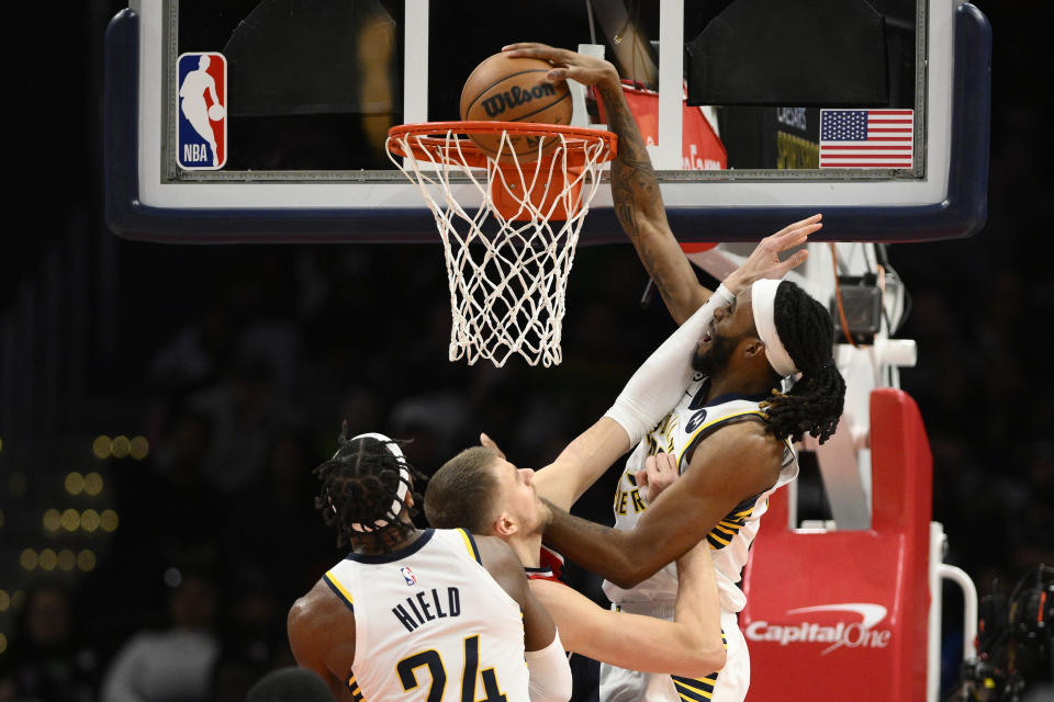 Indiana Pacers forward Isaiah Jackson, right, dunks over Washington Wizards center Kristaps Porzingis, center, during the first half of an NBA basketball game, Saturday, Feb. 11, 2023, in Washington. Pacers guard Buddy Hield is at front. (AP Photo/Nick Wass)