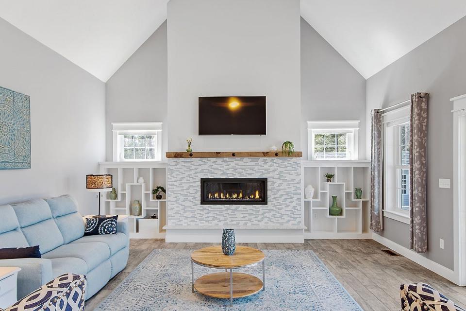 The living room has a vaulted ceiling and unique gas fireplace flanked by artisan-style built-in shelving.