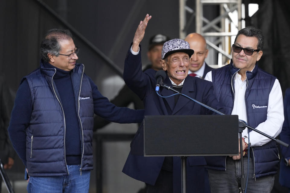 El presidente de Colombia, Gustavo Petro, a la izquierda, escucha las palabras de José del Carmen Estepa, de 89 años, en la firma de la reforma al sistema de pensiones, una de las promesas de campaña del mandatario para que los adultos en edad de retiro que viven en condición de pobreza reciban una renta básica del Estado, en Bogotá, Colombia, el martes 16 de julio de 2024. (AP Foto/Fernando Vergara)