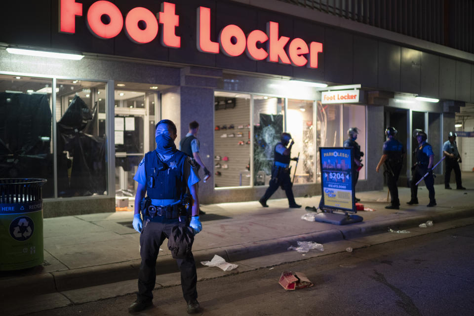 Minneapolis Police stand outside a looted Foot Locker store on S. 7th St., Wednesday, Aug. 26, 2020 in Minneapolis. The Minneapolis mayor imposed a curfew Wednesday night and requested National Guard help after unrest broke out downtown following what authorities said was misinformation about the death of a Black homicide suspect. (Jeff Wheeler/Star Tribune via AP)