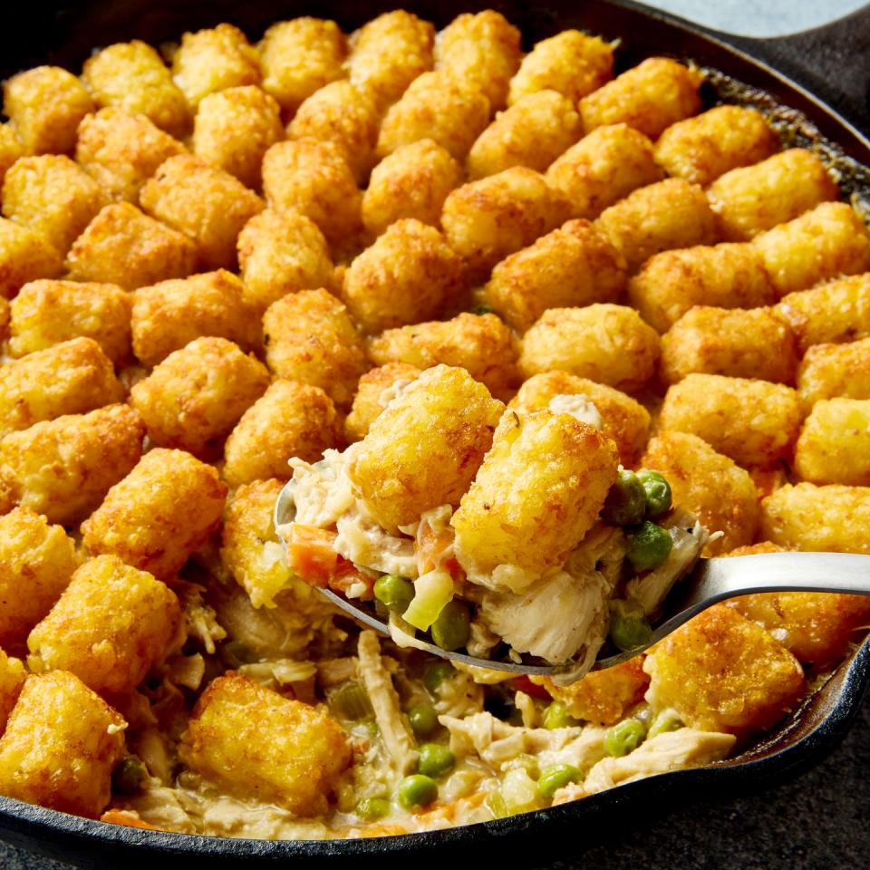 chicken pot pie filling in a skillet topped with tater tots