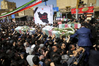 Mourners carry flag-draped caskets during a mass funeral for victims of Saturday's terror attack on a military parade, in the southwestern city of Ahvaz, Iran, Monday, Sept. 24, 2018. Thousands of mourners gathered at the Sarallah Mosque on Ahvaz's Taleghani junction, carrying caskets in the sweltering heat. (AP Photo/Ebrahim Noroozi)