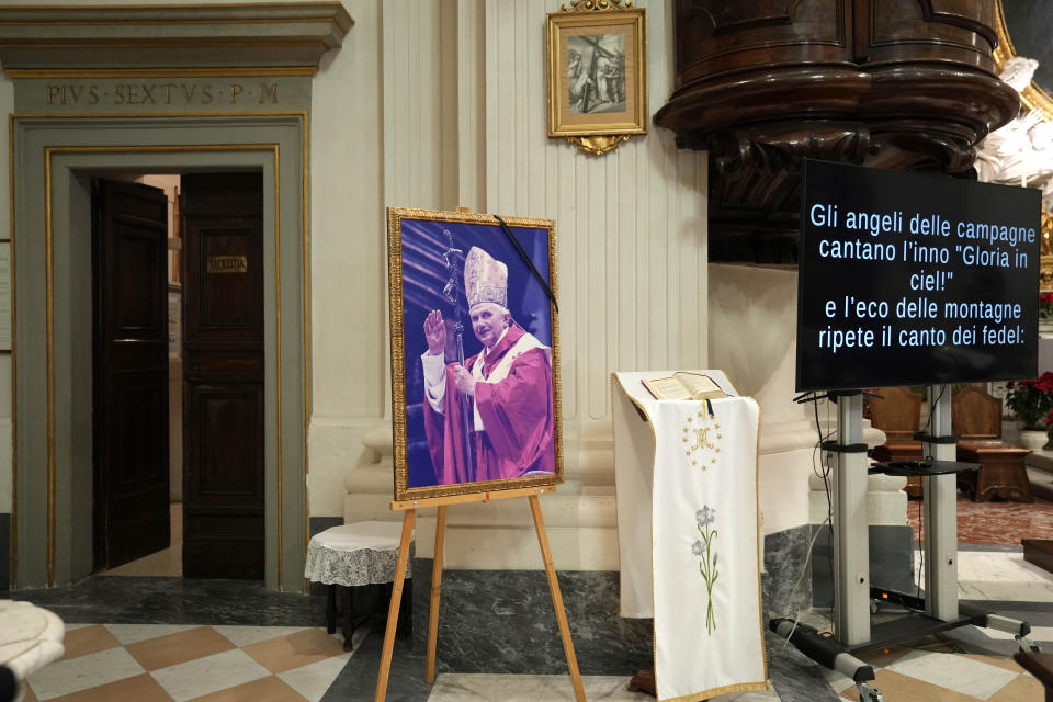 A photo of late Pope Emeritus Benedict XVI is displayed in the San Tommaso Da Villanova Parrish church in Castel Gandolfo, in the hills south of Rome, Tuesday Jan. 3, 2023. Benedict's death has hit Castel Gandolfo's "castellani" particularly hard, since many knew him personally, and in some ways had already bid him an emotional farewell on Feb. 28, 2013, when he uttered his final words as pope from the palace balcony overlooking the town square. (AP Photo/Alessandra Tarantino)