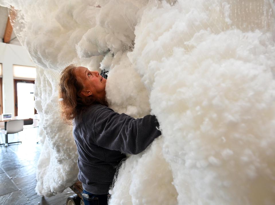New England Botanic Garden at Tower Hill volunteer Leslie Duthie of Monson holds up the bottom of nets of cotton representing clouds as employees create a thunderstorm exhibit. The New England Botanic Garden at Tower Hill in Boylston was setting up its 2022 Night Lights for the holidays.