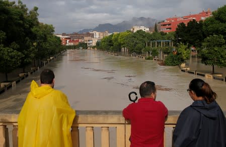 People look at the overflowing Segura river as torrential rains hit Orihuela