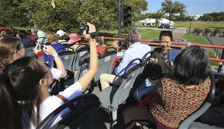 Tourists take pictures with the White House (right rear) atop a Big Bus double-decker tour bus in Washington October 2, 2013. REUTERS/Gary Cameron