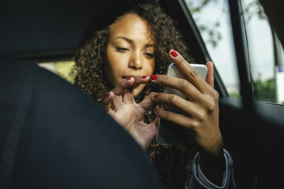 a woman on her phone in the back seat of a car