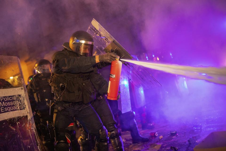 Un mosso usa un extintor para extinguir una barricada (AP Photo/Bernat Armangue)