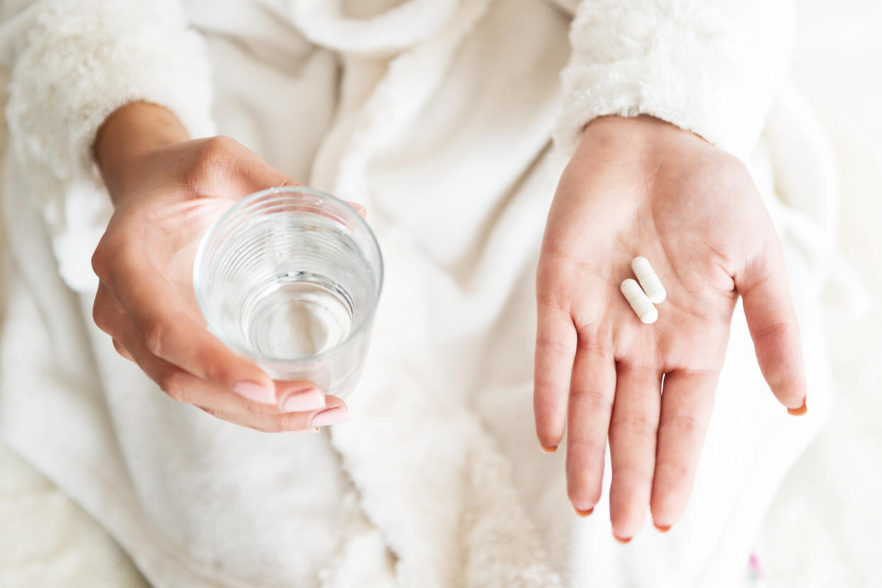 Woman holding a glass of water and pills, detail  