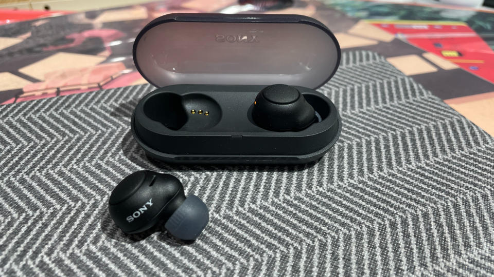 One Sony WF-C500 wireless earbud in and one out of its charging case