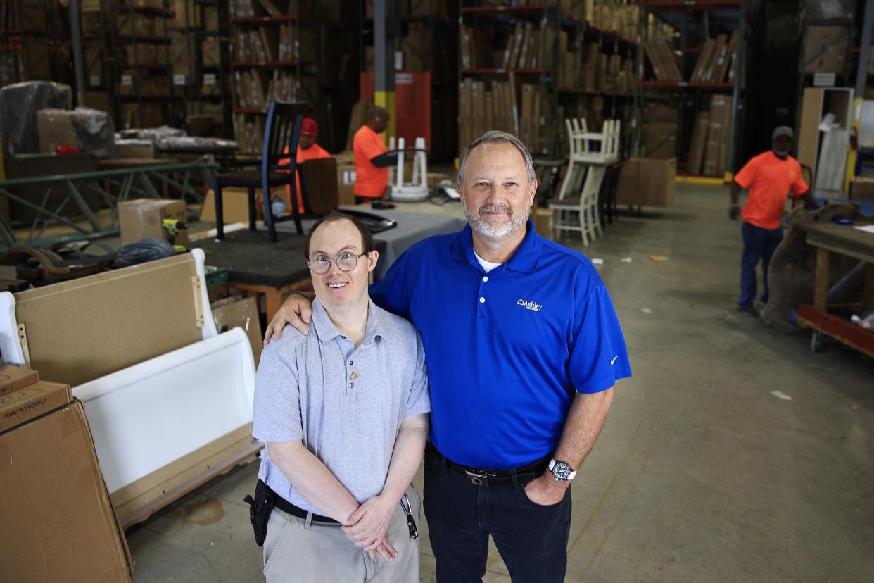 Andrew Hozier (left) and Greg King, vice president of Ashley HomeStore, pose at the Ashley warehouse where Hozier works assembling chairs. Hozier has Down syndrome.