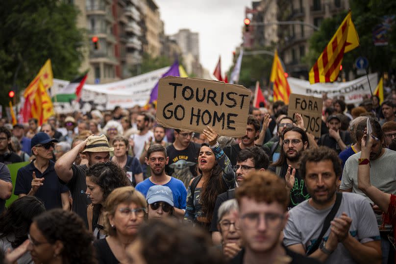 Manifestantes marchan gritando consignas contra el turismo excesivo, en el centro de Barcelona, el 19 de junio de 2024.