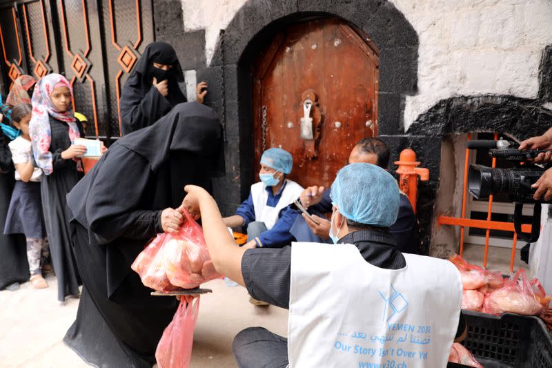 Worker gives a food ration to a woman at a charity kitchen in Sanaa