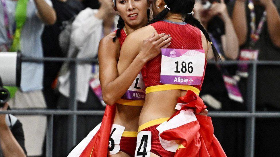 Las atletas chinas Yanni Wu y Yuwei Lin se abrazan tras correr los 100m con vallas