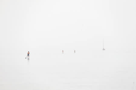 A sap surfer stands on a board in the Mediterranean Sea in Tel Aviv, Israel April 9, 2016. The picture was created by exposing for the shadows on a hazy day. REUTERS/Baz Ratner