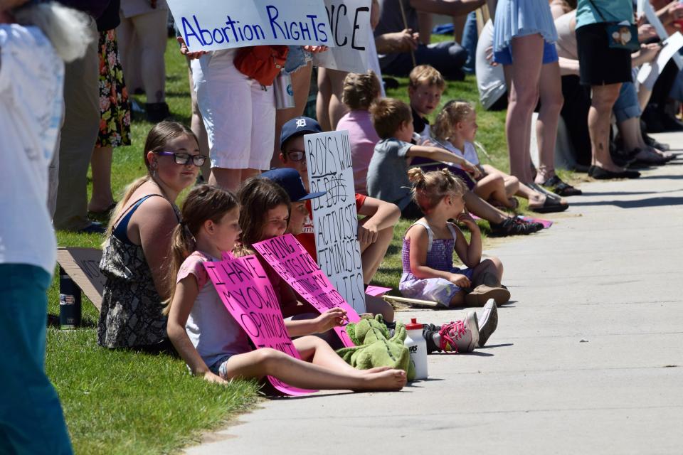 A group of kids hold pro-abortion rights signs along US-31 in front of the hole in downtown Petoskey on Sunday, July 3.