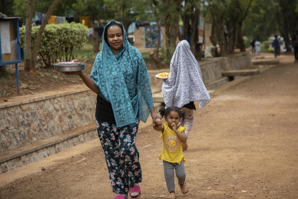 A woman who was evacuated from Libya to Rwanda carries a plate of food in the Gashora transit center for refugees and asylum-seekers, in the Bugesera district of Rwanda Friday, June 10, 2022. As Britain plans to send its first group of asylum-seekers to Rwanda amid outcries and legal challenges, some who came there from Libya under earlier arrangements with the United Nations say the new arrivals can expect a difficult time ahead. (AP Photo)