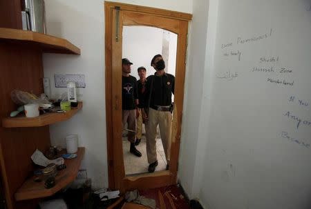 Police look at the destroyed door to the dorm room of Mashal Khan, accused of blasphemy, who was killed by a mob at Abdul Wali Khan University in Mardan, Pakistan April 14, 2017.REUTERS/Fayaz Aziz