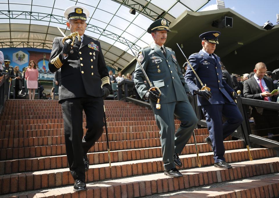 FILE - In this Dec. 17, 2018 file photo, Army Commander Gen. Nicacio Martinez Espinel, center, descends a flight of stairs during a swearing-in ceremony for the new military and police commanders, in Bogota, Colombia. New evidence has emerged linking Martinez Espinel to the alleged cover up of civilian killings more than a decade ago. The documents, provided to The Associated Press by a person familiar with an ongoing investigation into the extrajudicial killings, come as Martinez Espinel faces mounting pressure to resign over orders he gave troops this year, 2019, to step up attacks in what some fear could pave the way for a return of serious human rights violations. (AP Photo/Fernando Vergara, File)